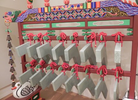 shaped and polished blocks of jade hanging from a wooden frame; this is a musical instrument called a lithophone
